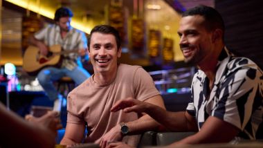 Guys talking with guitar player in background